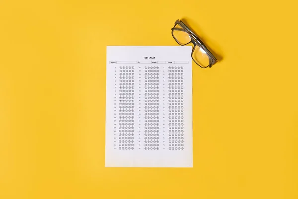 黄色の背景をした眼鏡の横の紙の上に目の図があります — ストック写真