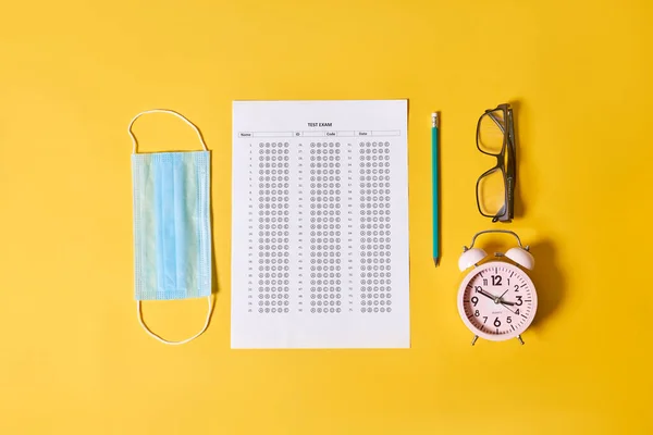 an office desk with a clock, eyeglasses, and a sheet of paper next to it on a yellow background