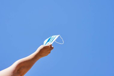 Birisi mavi gökyüzü arka planına bağlı bir iple uçurtmayı havada tutuyor.