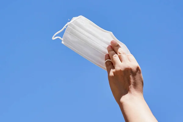誰かが空に白いプラスチック製のカップを持ってる雲の見えない青い空に対して — ストック写真