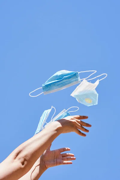 Beberapa Tangan Memegang Sepasang Masker Bedah Udara Terhadap Langit Biru — Stok Foto