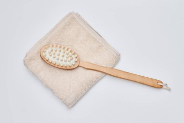 a wooden brush and towel on a white background with copy space in the bottom right hand is holding a toothbrush