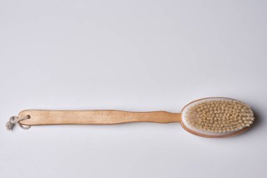 a wooden brush on a white background with copy space in the top right corner, and an image of a toothbrush next to