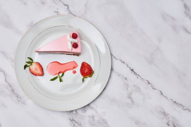 a piece of cake on a plate with strawberries and strawberrys next to it, sitting on a marble surface