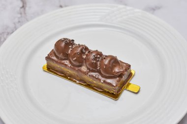 a piece of cake on a white plate with gold trim around the edge and chocolate drizing down the side