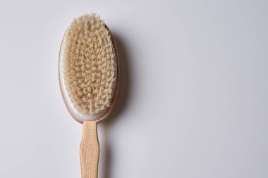 a wooden tooth brush on a white background with copy space in the bottom right hand is holding it up to the handle