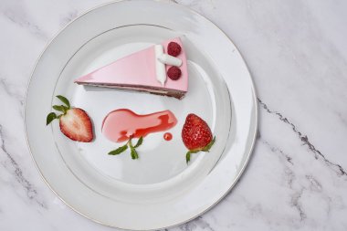 a piece of cake on a plate with strawberries and strawberrys next to it, sitting on a marble surface