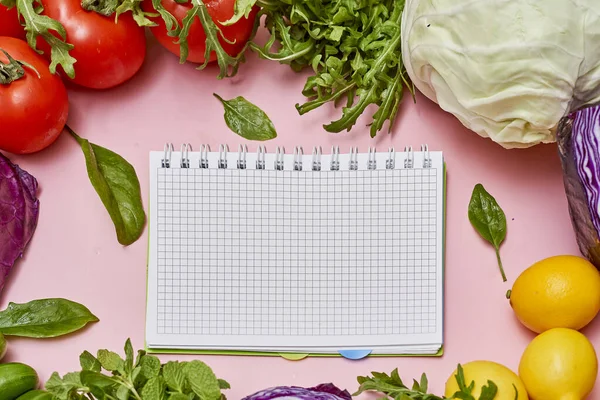 vegetables and a notepad on a pink background with space for your text or image to be written in the notes