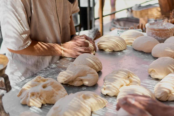 An An experienced baker outdoors in the shade prepares the dough with high quality flour to make organic bread. the concept of nature, healthy, food, diet and organic.experienced baker outdoors in the