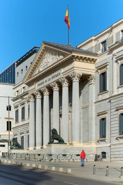 The iconic neoclassical facade of the Congress of Deputies, with its majestic columns and a golden lion statue guarding the main entrance, symbolizes Spanish political power