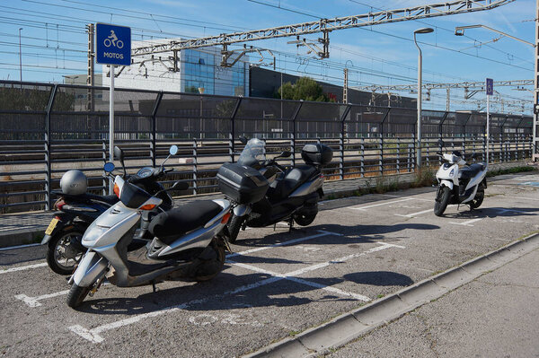 Гава - 27 мая 2023 года: Эксклюзивная стоянка для мотоциклов рядом с железнодорожным вокзалом с вертикальной вывеской, обозначающей его и разметкой земли, разделяющей каждое пространство
