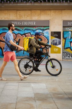 Barcelona, 12 Haziran 2023, Barcelona 'nın dar sokaklarından geçen bisikletli teslimatçı.