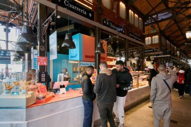 MADRID SPAIN - 05 Aralık 2023 Madrid 'deki Sant Miguel Pazarı bir churros standı ve önünde genç insanlarla meşgul.