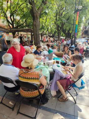 Barselona, İspanya - 20 Şubat 2024 Viladecanlar şehrinin bir mahallesinde insanların bobbin danteli yaptığı bir açık hava topluluk toplantısının görüntüsü