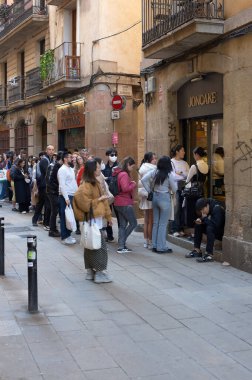Barselona, İspanya - 27 Şubat 2024: Bir grup insan Joncake mağazasının önünde sabırla bekliyor, günlük bir kentsel anı yakalıyorlar.