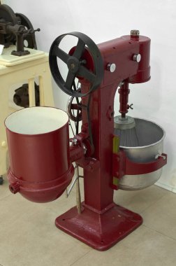 Çikolata yapımında kullanılan antika bir makinenin yakın çekimi, yıpranmış dişlileri ve mekanizmaları gösteriyor.