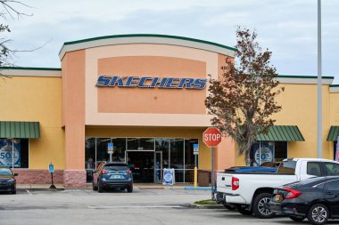Florida, ABD - 23 Mart 2024: Bir Skechers mağazasının ön yüzünü çeken canlı görüntü, göz alıcı levhası, mimari tasarımı ve açık bir gökyüzü altında park edilmiş arabaları sergiliyor.