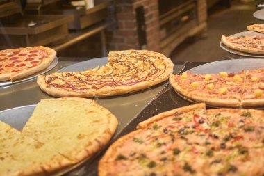 Görüntü, farklı içerikli, sıcak ve samimi atmosferi olan gurme pizzaları gösteriyor. Pizzalar taze pişmiş ve servis edilmeye hazır. Müşteriler için iştah açıcı oluyor..