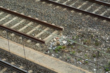 Tren raylarının doğa ile iç içe geçmiş havadan görünüşü taşların ve metallerin arasından çıkan yeşil bitkiler, organik yaşamla endüstriyel yapılar arasında çelişmektedir. Dayanıklılık ve kentsellik temaları için ideal.