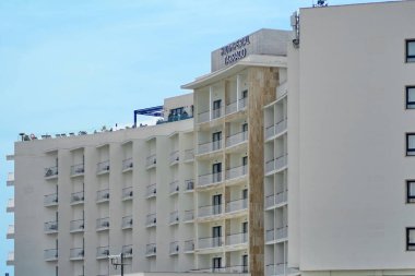 Tarragona, İspanya - 14 Nisan 2024: Hotel Imperial Tarragona, arka planda turistler ve gezginler için ideal simetrik balkonları ve berrak gökyüzü olan modern bir mimari yapıyı gösteriyor.