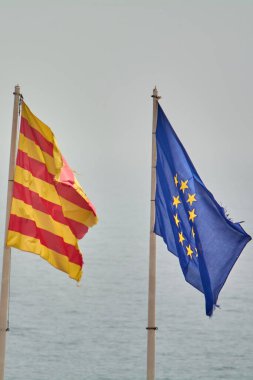 Flags of Catalonia and the European Union flutter in perfect harmony over a clear sky, representing European union and solidarity. clipart
