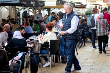 Tarragona, İspanya - 21 Nisan 2024: Müşterilerin içki ve yemeklerden keyif aldığı kalabalık açık hava kafe teras sahnesi kentsel eğlence ve sosyal yemek deneyiminin bir örneği.