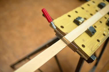 Testerenin yakın plan görüntüsü tezgahın üzerine tutturulmuş bir tahta parçası, marangozlukta hassasiyet ve teknik beceriyi vurguluyor..