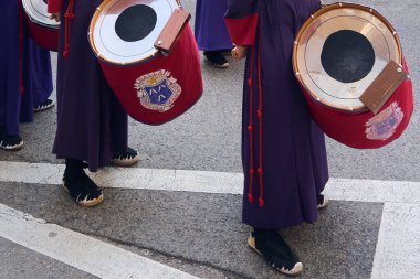 Tarragona, İspanya - 26 Nisan 2024: Tarragona 'da bir sokakta kutsal haftanın özü. Geleneksel davullar ve mor elbiseler etkinliğin zengin kültürünü ve geleneğini ön plana çıkarıyor.