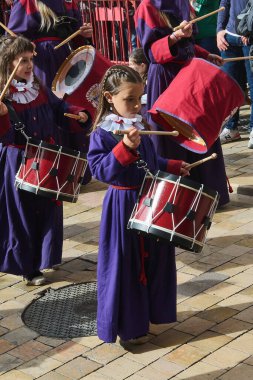 Tarragona, İspanya - 26 Nisan 2024: Mor cüppeli çocuklar kültürel ve dini kutlamaların ruhunu yansıtan bir törende davul çalıyorlar.