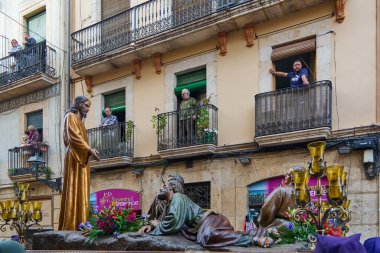Tarragona, İspanya - 27 Nisan 2024: Kutsal Hafta 'da kutsal heykeller geçerken sadık insanların balkonlarından izledikleri tipik İspanyol sahnesi.