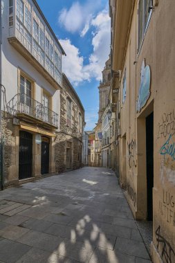 Lugo, İspanya - 29 Nisan 2024: Lugo 'da tarihi binalar arasında yükselen heybetli katedral kulesi ile panoramik bir cadde manzarası.