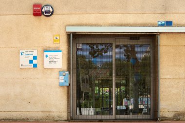 Viladecanlar, Barselona, İspanya-26 Mayıs 2024: Duvarında kapalı kapılar ve bilgi tabelaları olan İspanya Devlet Tıp Merkezi. Kapının üzerinde bir acil durum aygıtı görebilirsiniz..