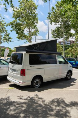 Şehir ortamında ağaçların arasına park edilmiş, üstü açılır çatısı olan maceraya hazır bir karavan..