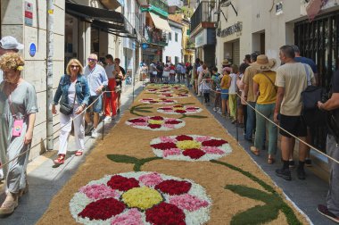 Sitges, Barcelona, İspanya-Haziran 03-2024: Halk, özel bir etkinlik sırasında sokakları geçici ve renkli bir duvar halısına dönüştüren yerel yetenekleri takdir etmek için toplandı..