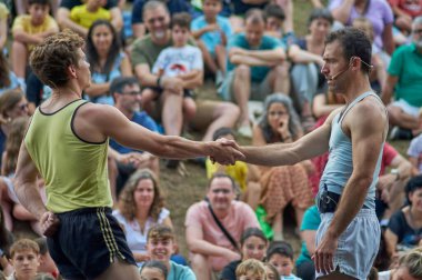 Viladecasn, İspanya - 12 Temmuz 2024: İki sporcu kalabalık bir spor etkinliğinde el sıkışıyor, rekabetin ortasında sportmenliği ve dostluğu simgeliyor.