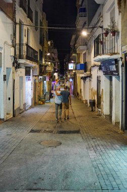 Sitges, Barcelona-Eylül 04.2024: Dar bir yaya geçidinde yerel cazibe ve tipik mimari ile canlı bir gece.