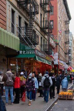 New York, ABD - 14 Eylül 2024: Çin tabelaları ve tipik New York yangın çıkışları olan dükkanlar arasında yürüyen insanlarla dolu bir cadde.