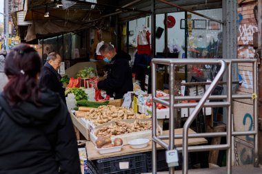 New York, ABD -15 Eylül 2024: Maskeli bir satıcıyla birlikte Çin Mahallesi, NYC 'deki bir markette taze sebze standı. Görüntü, şehir hayatının canlılığını ve dinamizmini yansıtıyor..