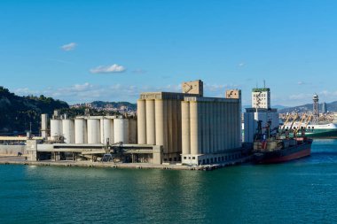 Barcelona, Spain - September 28, 2024: An aerial view of the industrial port of Barcelona with grain silos and a cargo ship for loading and unloading. clipart