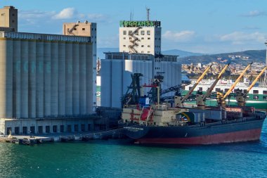 Barcelona. Espain -October 20,2024: Port of Barcelona, with a cargo ship docked next to silos with multiple cargo cranes operating. A visual representation of modern maritime transport and clipart