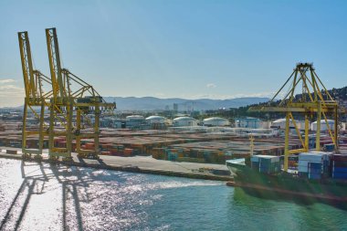 Barcelona. Espain -October 20,2024: Port of Barcelona, with multiple cranes and a cargo ship full of containers being unloaded. clipart