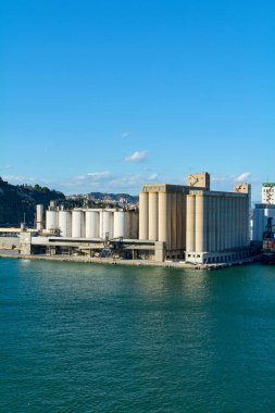 Barcelona. Espain -October 20,2024: Aerial view of the industrial port of Barcelona with grain silos under a blue sky and a calm sea. clipart