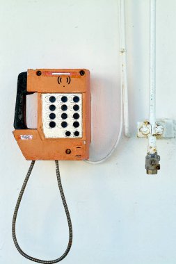 Bu görüntü bir geminin beyaz duvarına sabitlenmiş nostaljik bir deniz telefonu yakalıyor, eski dünya iletişim araçlarını minimalist bir ortamın basitliğiyle harmanlıyor. Klasik ve deniz teması için mükemmel