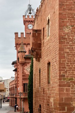 Viladecanlar. İspanya - 7 Kasım 2024: Viladekan belediye binasındaki tarihi taretin büyüleyici görüntüsü, detaylı tuğla işçiliği ve mimari alanları yansıtan renkli çatı kiremitlerini vurguluyor