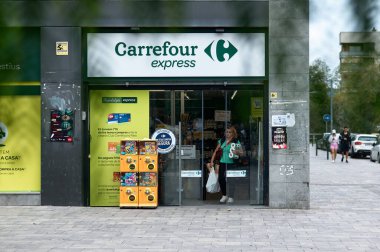 Viladecanlar. İspanya - 7 Kasım 2024: Bir Carrefour Express mağazası, çeşitli tanıtım materyalleri ve temiz markalar sergileyen bir müşteri ile birlikte. Kentsel çevre,