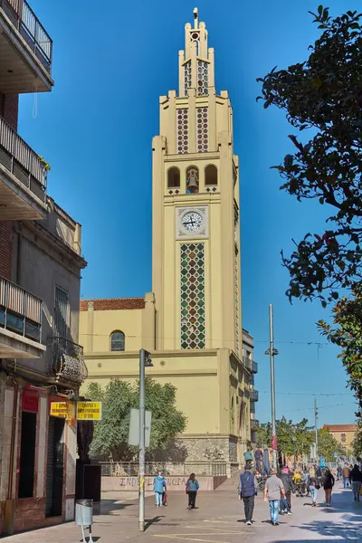 Montcada i Reixac. İspanya - 11 Kasım 2024: Montcada i Reixac kilisesinin saat kulesinin manzarası, eşsiz mimarisi ve canlı kasaba meydanı, yayalar ve aydınlık, güneşli bir gün.