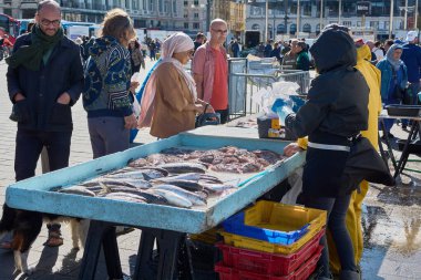 Marsilya. Fransa - 20 Kasım 2024: Marsilya 'nın Eski Limanı' ndaki balıkçı, yerli ve turistlere çeşitli taze deniz ürünleri sunuyor. Satıcının tezgahı, geleneksel pazar atmosferini yansıtan bir dizi balıkla dolu..