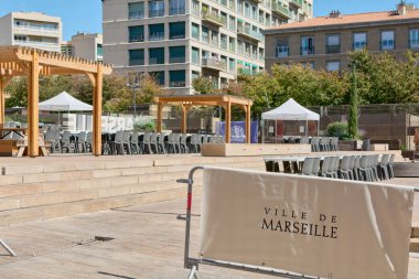 Marsilya. Fransa - 27 Kasım 2024: Marsilya 'da ahşap pergolalı, sayısız sandalye ve çevresindeki binalarla çağdaş bir kentsel alan, sosyal etkinlikler ve toplumsal faaliyetler için ideal.