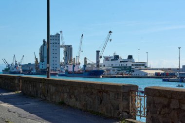 Savona. İtalya - 07 Aralık 2024: Liman gemilerinin, operasyonel vinçlerin ve deniz lojistiğinin karmaşıklığını gösteren sanayi binalarının yer aldığı aktif bir nakliye limanının ayrıntılı görüntüsü