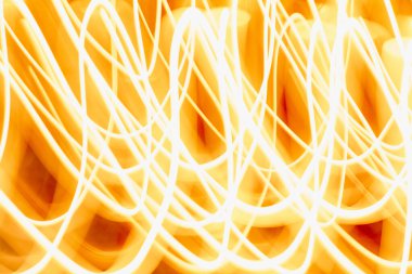 Turuncu bir zemin üzerinde parlak, kıvrımlı ışık çizgileri karmaşık desenler oluşturuyor, sanatsal ve yaratıcı kullanım için dinamik ve canlı bir görsel ideal sunuyor..